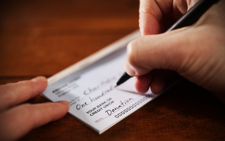 Writing a donation check to a charitable organization. Philanthropic giving and risk management.